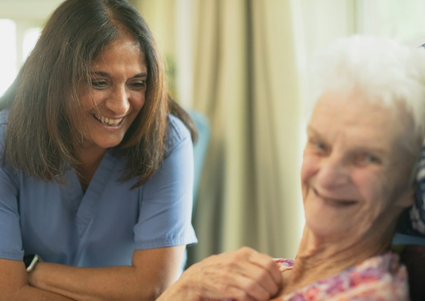 A nurse sharing a laugh with an older patient at home