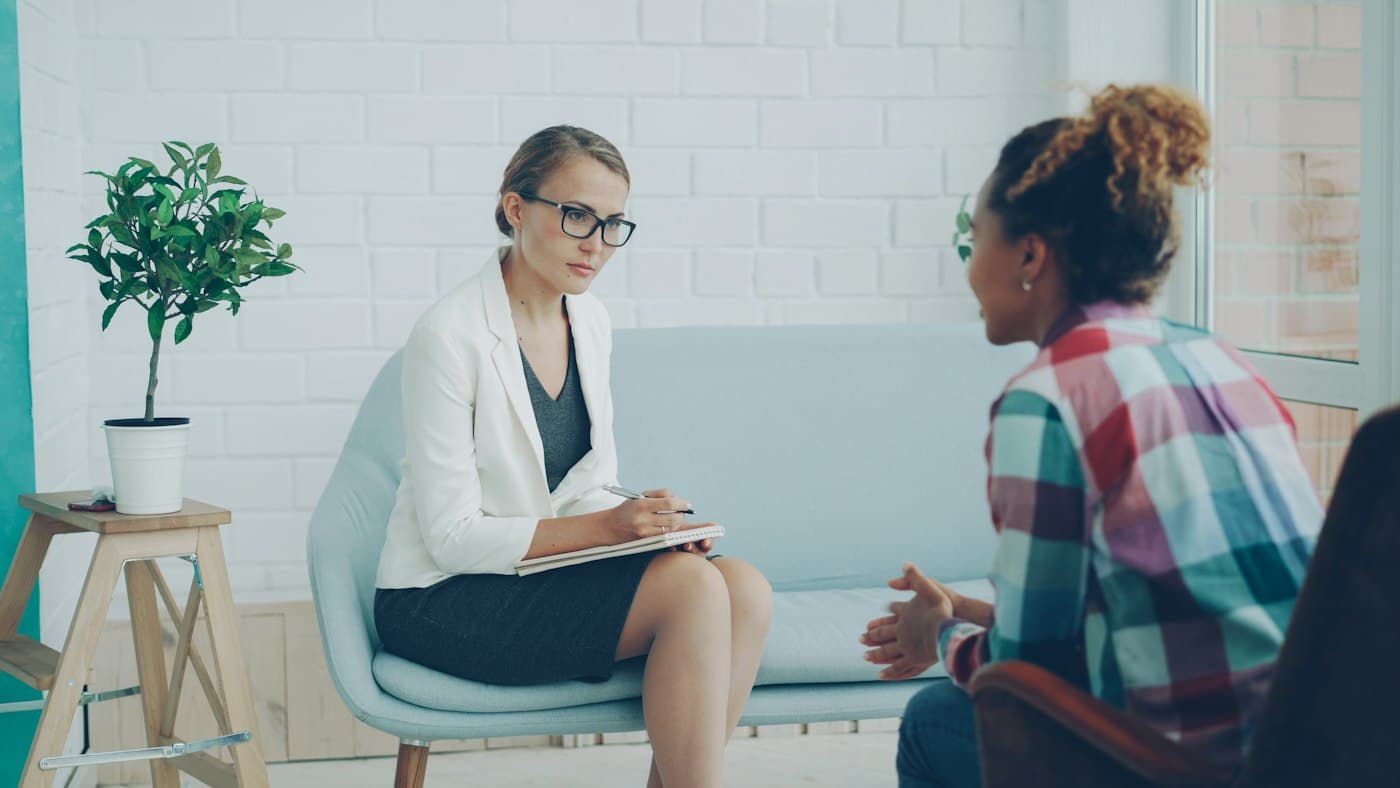 Two people talking calmly in a warm, quiet counselling room